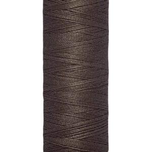 A spool of Gütermann thread in brown, with labels indicating 100 meters and 110 yards. The thread is neatly wound around a beige cylindrical spool.