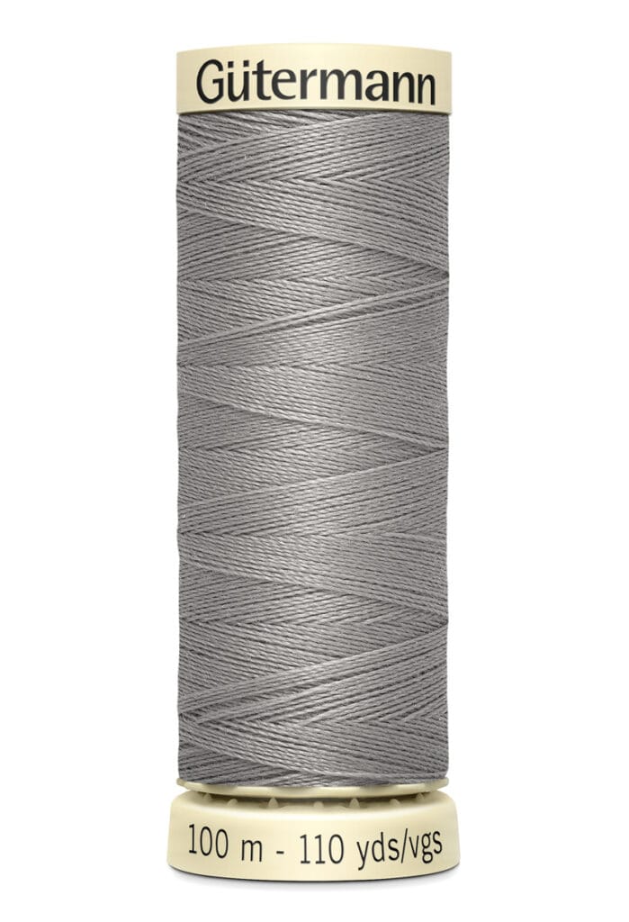 A spool of Gütermann gray sewing thread is shown vertically. The label reads "100 m - 110 yds/vgs." The thread is neatly wound around the spool, which is cream-colored at both ends.