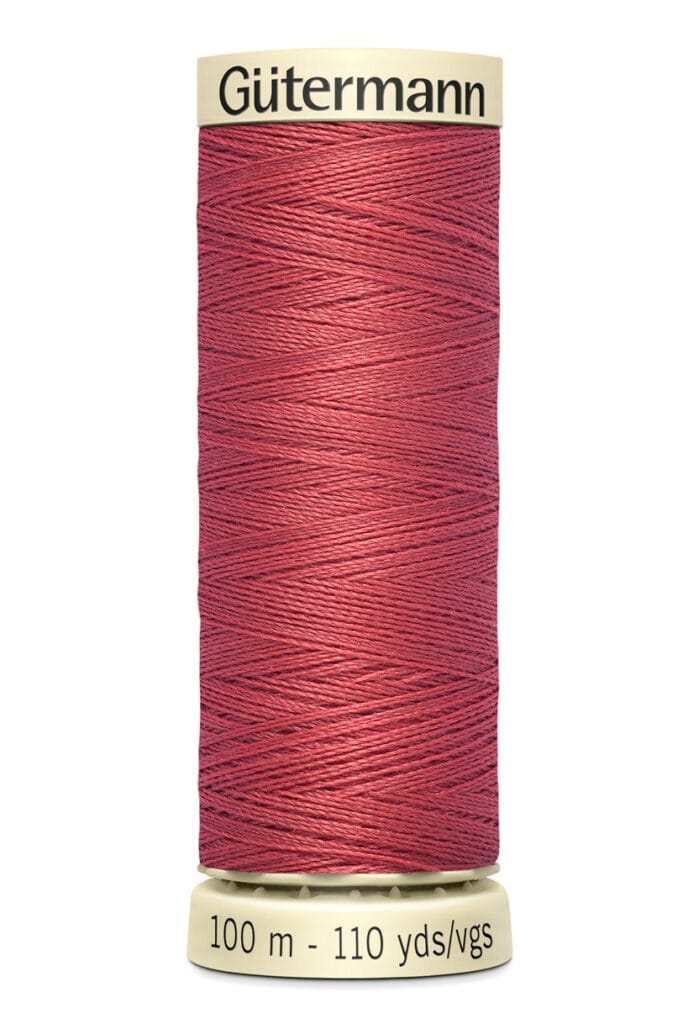 A spool of Gütermann thread in deep red. The spool is labeled with "100 m - 110 yds/vgs" and has a cream-colored top and bottom. The thread is neatly wound around the spool.