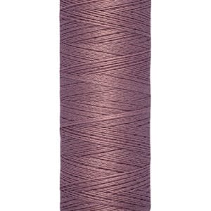 A spool of Gütermann sewing thread in a dusty purple color, wrapped neatly around a cream-colored cylindrical base. The label indicates the length as 100 meters or 110 yards.