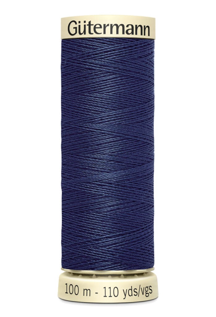 A spool of Gütermann sewing thread in navy blue. The label shows it contains 100 meters (110 yards) of thread. The spool is cylindrical with a beige top and bottom.