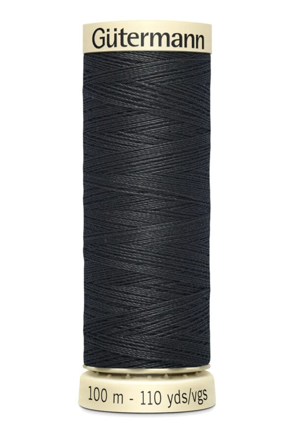 A spool of Gütermann black sewing thread, labeled with "100 m - 110 yds/vgs" on the bottom and "Gütermann" on top, features tightly wound thread on a cylindrical spool with a beige top and base.