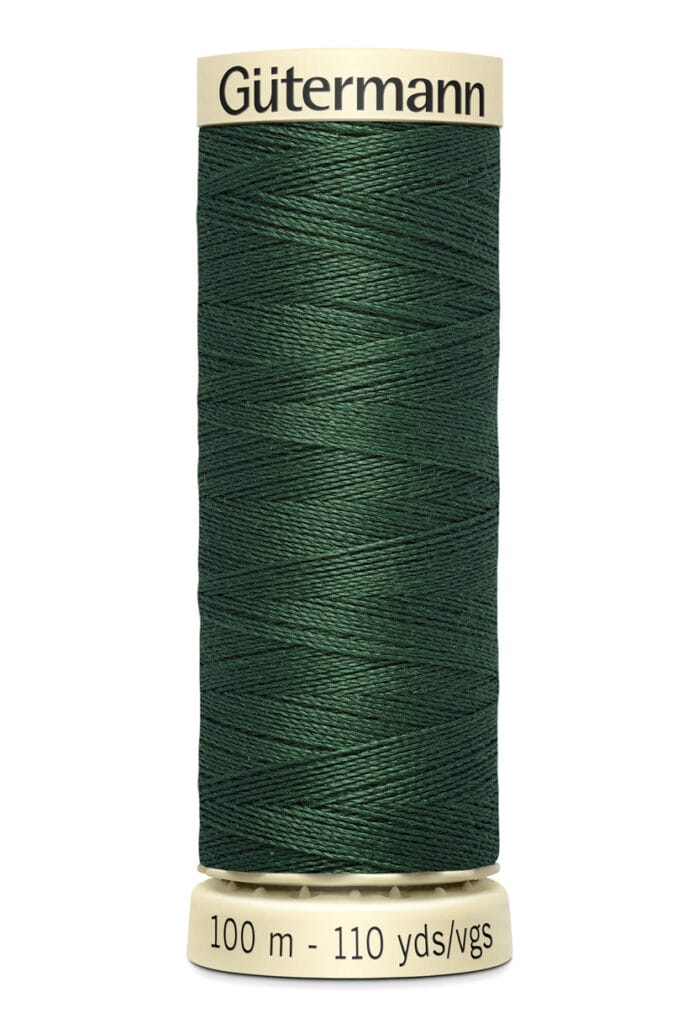 Close-up of a spool of Gütermann sewing thread in dark green. The label on top and bottom of the spool shows "Gütermann" and "100 m - 110 yds/vgs" in black text on a beige background.