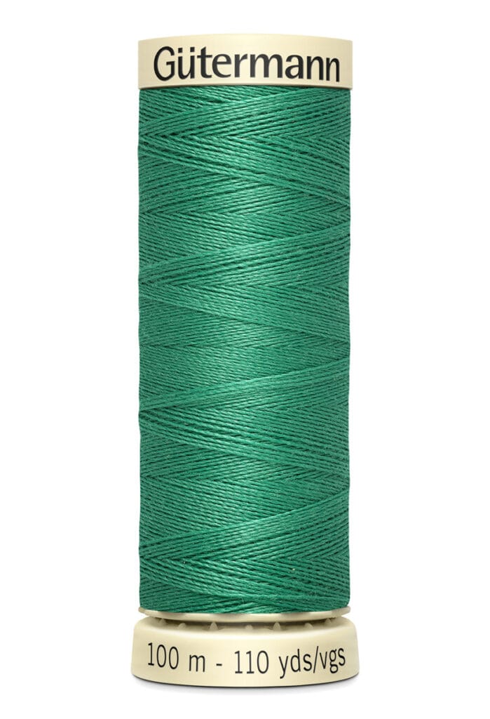 A spool of Gütermann green sewing thread with a label indicating 100 meters or 110 yards.