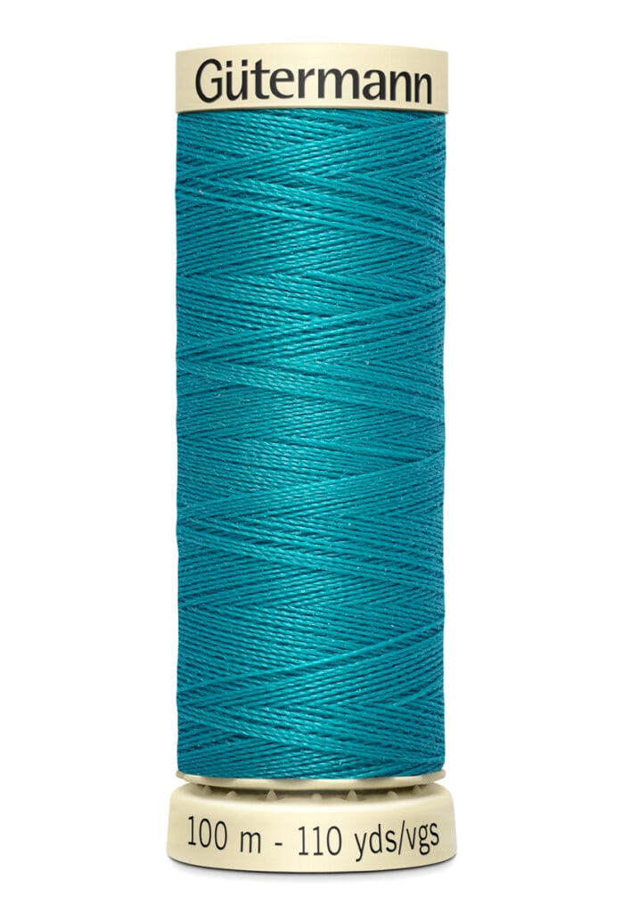 A spool of Gütermann thread in vibrant teal color, labeled with "100 m - 110 yds/vgs" on a beige base. The thread is neatly wound around the spool.