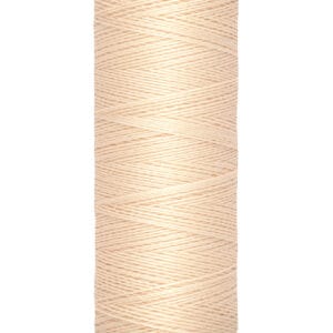 A spool of Gütermann thread with a soft beige color, labeled with 100 meters and 110 yards. The spool has a cream-colored top and bottom, displaying the brand name. The thread is neatly wound around the spool.