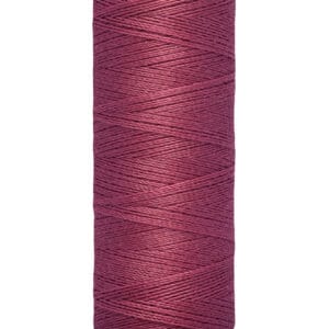 A spool of Gütermann thread with a burgundy color. The label indicates it contains 100 meters or 110 yards of thread. The spool is cylindrical with cream-colored ends and the brand name is printed on the top edge.