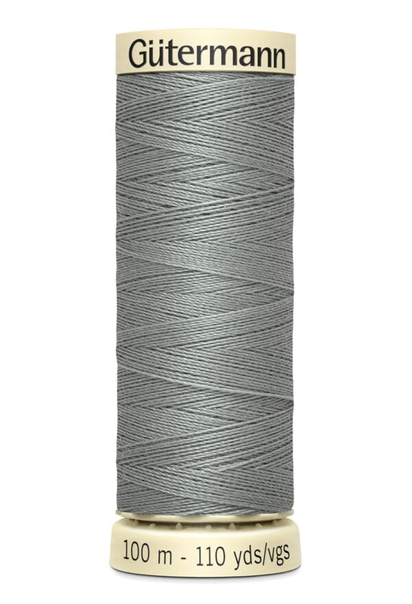 A spool of Gütermann sewing thread in a light gray color, with 100 meters (110 yards) indicated on the label. The spool is cylindrical and the label is cream-colored with black text.