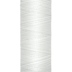 A spool of Gütermann sewing thread sits vertically. It is off-white and has a label indicating 100 meters or 110 yards of thread. The spool is cylindrical with a beige cap.