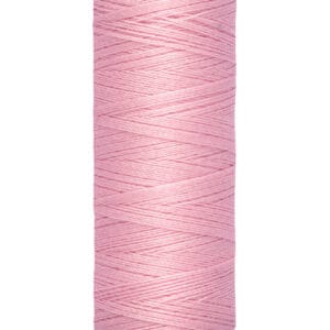 A spool of Gütermann thread in light pink, with a label showing 100 meters or 110 yards. The thread is neatly wound on a cream-colored spool.