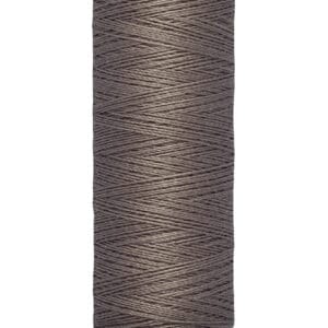 A spool of Gütermann gray thread is pictured. The spool holds 100 meters or 110 yards of thread and has a beige base and top. The tightly wound thread showcases a diagonal pattern.