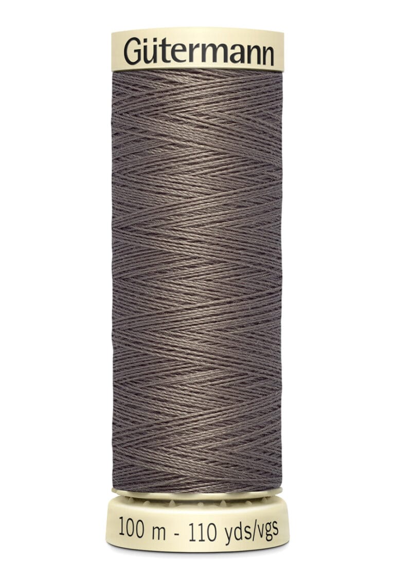 A spool of Gütermann gray thread is pictured. The spool holds 100 meters or 110 yards of thread and has a beige base and top. The tightly wound thread showcases a diagonal pattern.