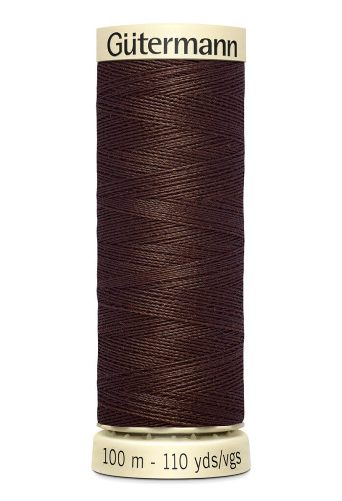 A spool of Gütermann thread in dark brown color, labeled with "100 m - 110 yds/vgs." The label is cream-colored with black text. The thread is neatly wound around the spool.