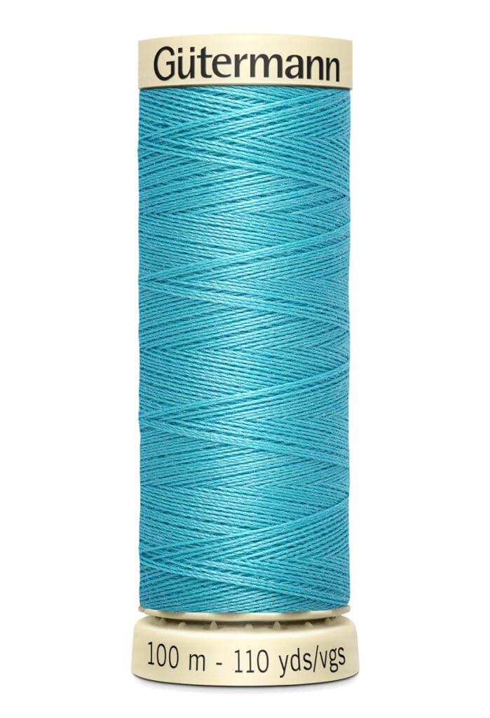 A spool of Gütermann sewing thread in bright turquoise. The label shows 100 meters and 110 yards. The spool is beige with the brand name at the top. The thread is neatly wound around the spool.