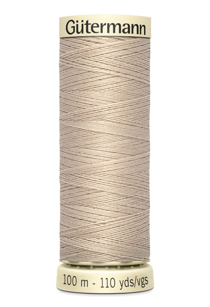 A spool of Gütermann thread in beige, labeled "100 m - 110 yds/vgs," with "Gütermann" written on the top. The thread is neatly wound around the spool.
