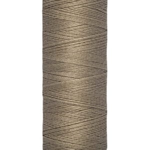 A spool of Gütermann thread in a beige color, labeled as 100 meters or 110 yards. The spool has a light yellow base and top, with the brand name printed on the top part.