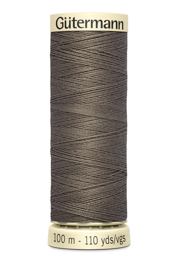 A spool of Gütermann thread in a dark gray color. The spool indicates the thread length of 100 meters or 110 yards. The top and bottom parts of the spool are a pale cream color, with the brand name displayed at the top.