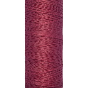 A spool of Gütermann thread, deep red in color, with a label showing "100 m - 110 yds/vgs." The spool has cream-colored ends with the brand name displayed at the top.