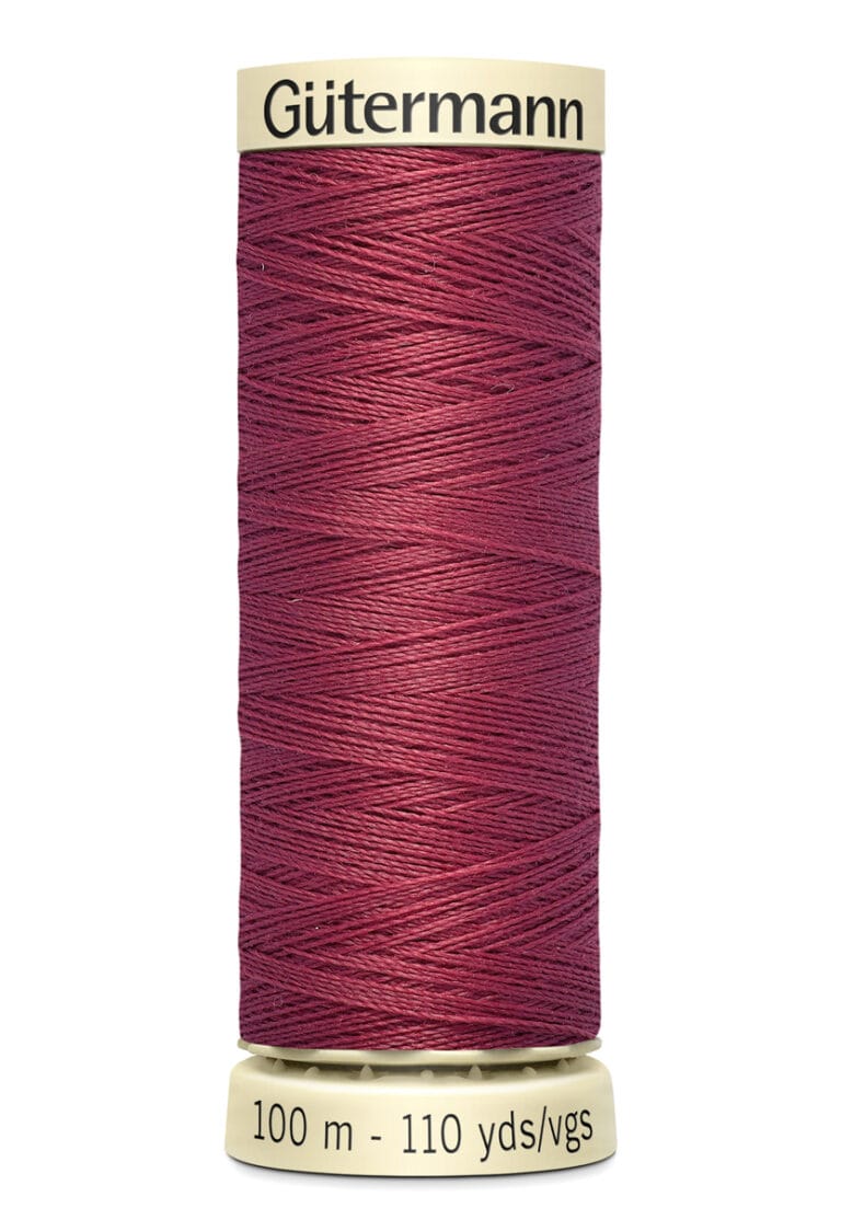 A spool of Gütermann thread, deep red in color, with a label showing "100 m - 110 yds/vgs." The spool has cream-colored ends with the brand name displayed at the top.