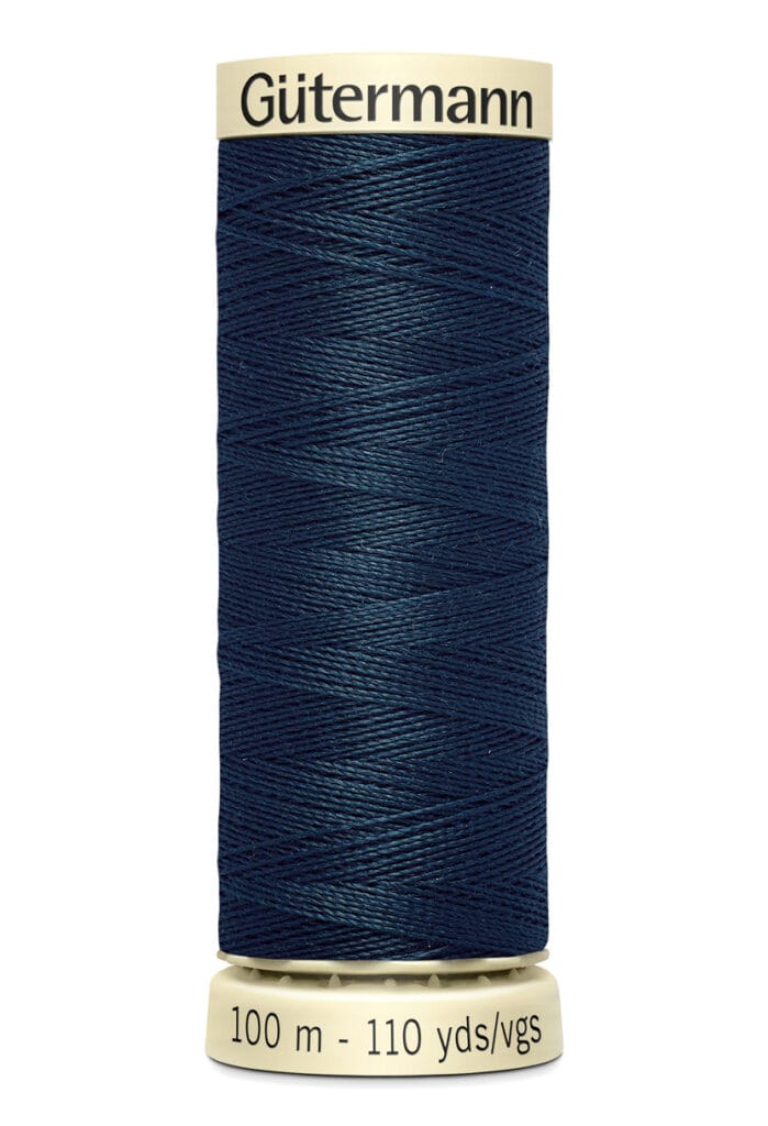 A spool of Gütermann dark blue sewing thread with a beige top and bottom. The label reads "100 m - 110 yds.