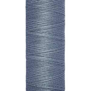 A spool of Gütermann sewing thread in denim blue. The spool is labeled with "100 m - 110 yds/vgs" and has a beige top and bottom. The thread is neatly wound and displayed against a plain white background.