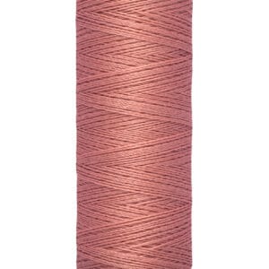 A spool of brownish-pink Gütermann sewing thread with cream-colored ends, labeled with "Gütermann" on the top and "100 m - 110 yds" on the bottom. The thread is neatly wound around the spool.