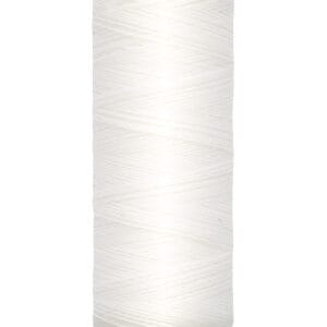 A spool of Gutermann thread with cream-colored thread wrapped around it. The label on top reads "Gütermann," and the base indicates "100 m - 110 yds/vgs.