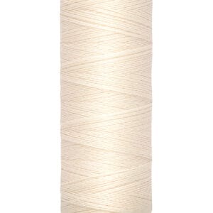 A spool of Gütermann sewing thread in cream color is centered in the image. The label reads "Gütermann" at the top and "100 m - 110 yds/vgs" at the bottom. The spool has a beige base.