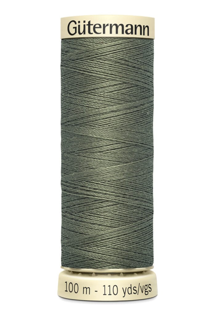 A spool of Gütermann thread in olive green, with labels indicating "100 m - 110 yds/vgs." The thread is uniformly wound on a beige spool.