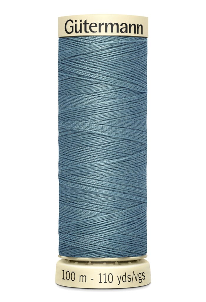 A spool of Gütermann thread in blue, with cream-colored top and bottom caps. The label indicates the thread is 100 meters (110 yards) in length. The thread is neatly wound around the spool.