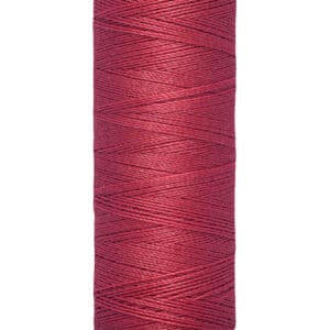 A spool of Gütermann thread in a deep red color, with labels indicating 100 meters and 110 yards on the bottom. The spool has a beige top and bottom.