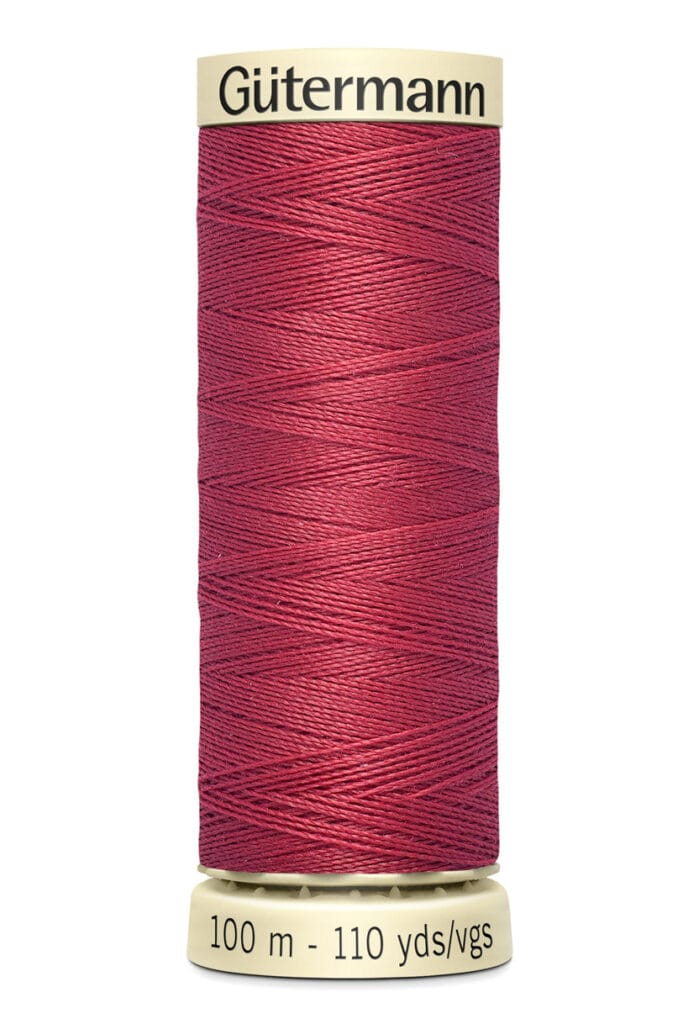 A spool of Gütermann thread in a deep red color, with labels indicating 100 meters and 110 yards on the bottom. The spool has a beige top and bottom.