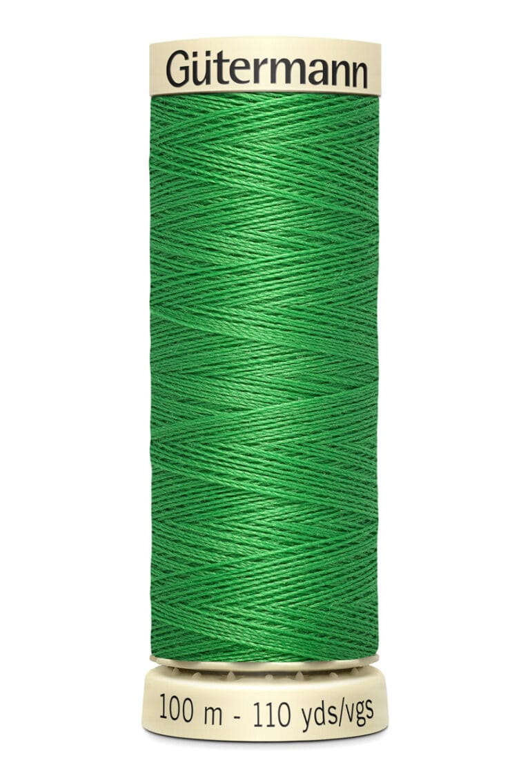 A spool of Gütermann green sewing thread is vertically oriented. The label on top shows the brand name, and the base indicates 100 meters or 110 yards of thread. The thread is tightly wound around the spool.