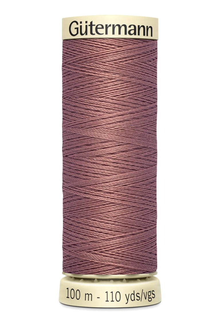 Spool of Gütermann thread in a dusty rose color, displayed vertically. The label states 100 meters or 110 yards. The thread is wound neatly around the spool, which has a light beige color with product branding at the top.