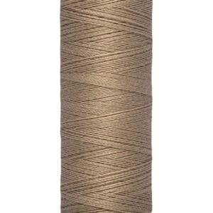 A spool of Gütermann brown sewing thread. The label reads "100 m - 110 yds/vgs." The spool has a cream-colored top and bottom with the brand name printed in black on the top.