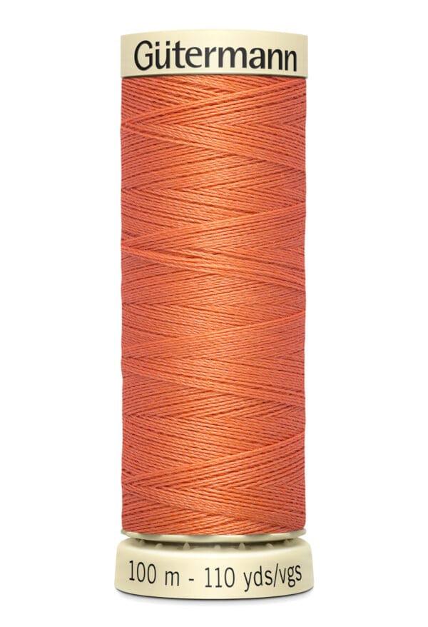 A spool of Gütermann sewing thread in a salmon color. It's neatly wound around a cylindrical cardboard holder that displays "Gütermann" at the top and "100 m - 110 yds" at the bottom.