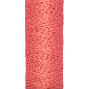 A spool of Gütermann thread in coral pink color, labeled with "100 m - 110 yds" on the base.