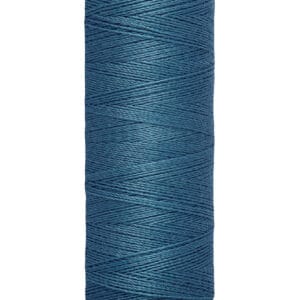 A spool of Gütermann thread in a deep teal color. The spool displays "Gütermann" on the top and "100 m - 110 yds" on the bottom. The thread is neatly wound around the cream-colored spool.