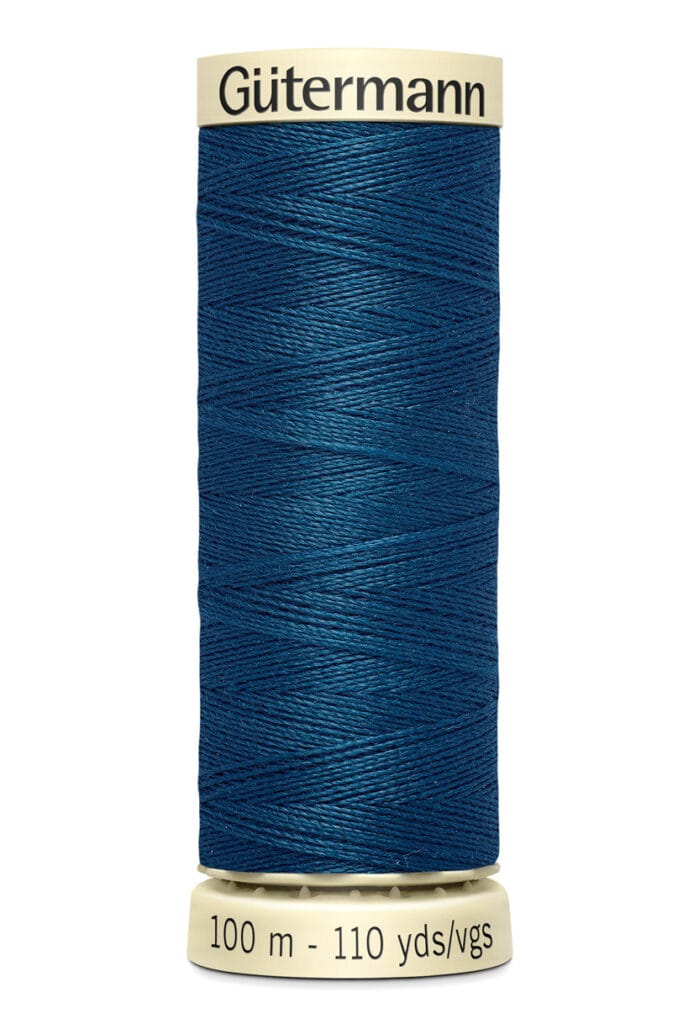 A spool of Gütermann thread in dark blue, wound tightly on a cream-colored holder. Text on the holder reads "100 m - 110 yds/vgs," indicating the length of the thread.