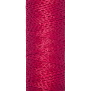 A spool of Gütermann thread, wrapped in vibrant red thread. The label reads "100 m - 110 yds/vgs" in black text on a beige background.