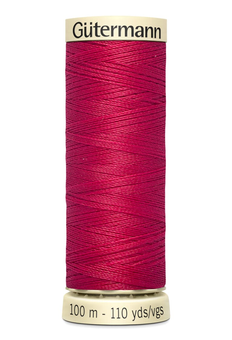 A spool of Gütermann thread, wrapped in vibrant red thread. The label reads "100 m - 110 yds/vgs" in black text on a beige background.