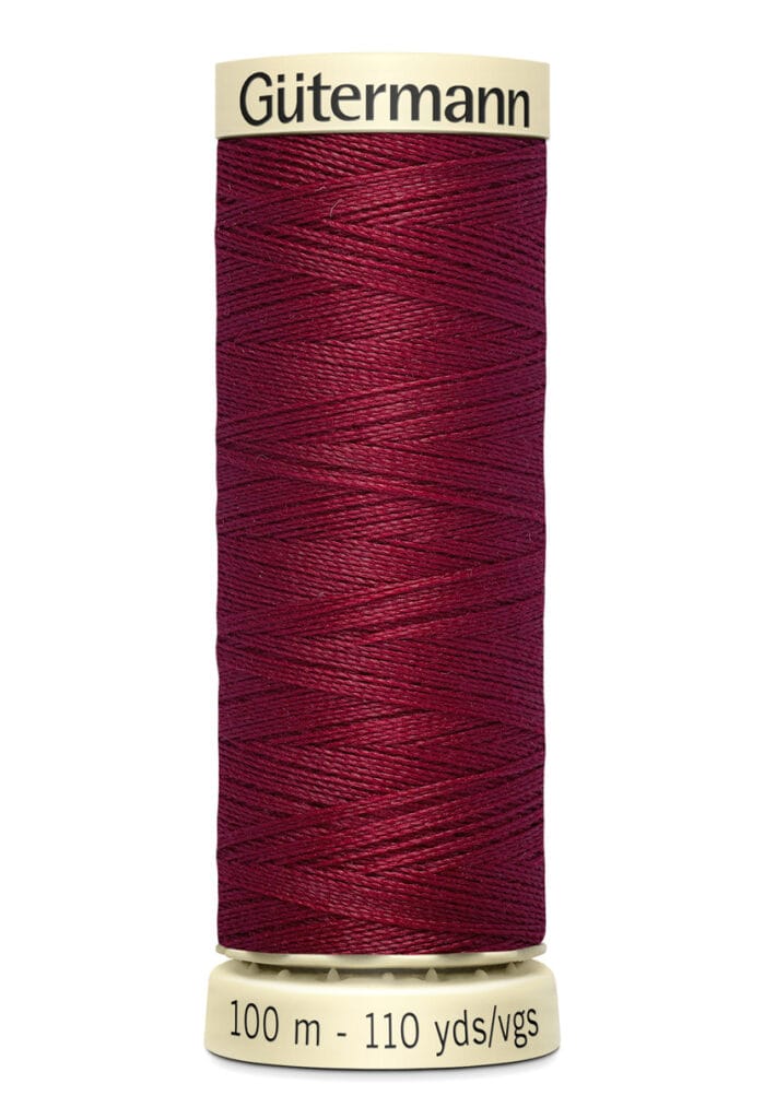 A spool of Gütermann thread with deep red color, wrapped neatly around a beige spool. The label on the bottom reads "100 m - 110 yds/vgs.