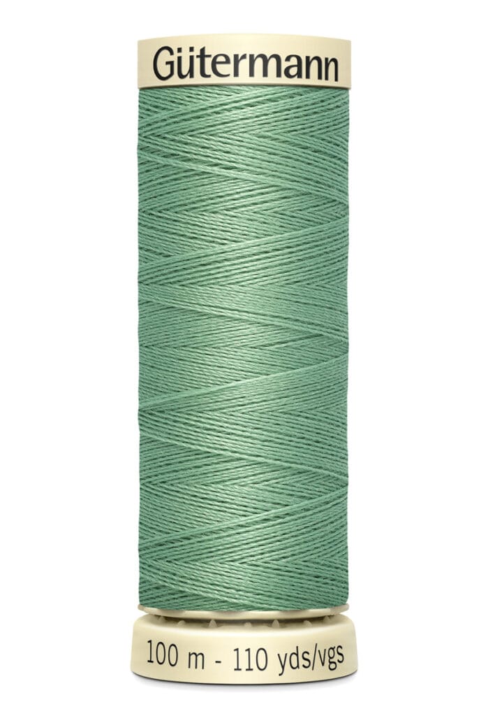 A spool of Gütermann sewing thread in a teal color. The spool shows "100 m - 110 yds/vgs" indicating the length of the thread. It has a beige top and bottom.