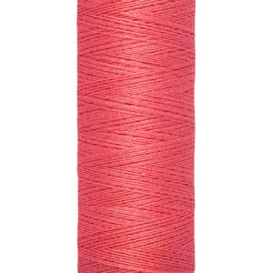 A spool of Gütermann red sewing thread. The label shows "100 m - 110 yds/vgs" indicating the length of the thread. The spool is cylindrical with cream-colored ends.