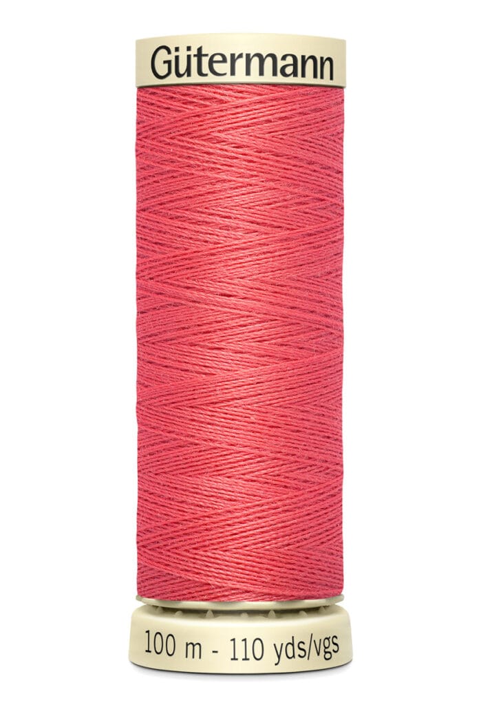 A spool of Gütermann red sewing thread. The label shows "100 m - 110 yds/vgs" indicating the length of the thread. The spool is cylindrical with cream-colored ends.