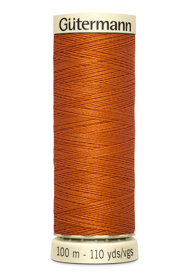 A spool of Gütermann thread in a warm orange hue, labeled on the base with "100 m - 110 yds/vgs.