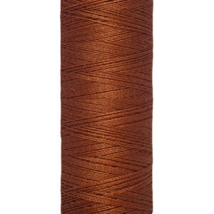 A spool of Gütermann thread, colored in a deep brown shade, is shown upright. The label at the bottom reads "100 m - 110 yds/vgs." The spool has a creamy white top and bottom edge.