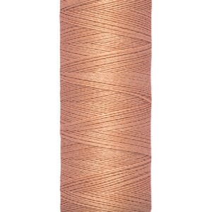 A spool of Gütermann thread in a dusty pink color, with 100 meters or 110 yards indicated on the bottom. The thread is neatly wound and the spool has a beige top and bottom.