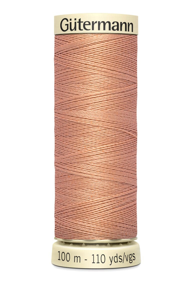 A spool of Gütermann thread in a dusty pink color, with 100 meters or 110 yards indicated on the bottom. The thread is neatly wound and the spool has a beige top and bottom.