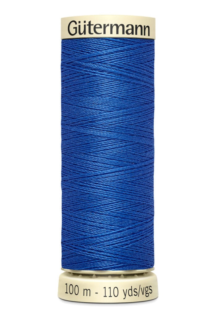 A spool of Gütermann blue sewing thread, labeled with "100 m - 110 yds/vgs". The thread is tightly wound on a beige plastic reel, with the brand name printed on the top.